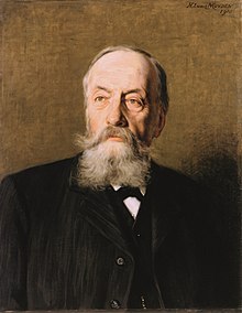 A portrait of a man with grey beard and moustache, wearing a black suit.