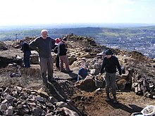 A group of archaeologists digging, with rubble in the foreground.