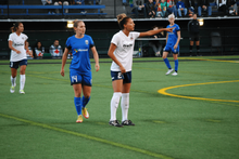 Woman in blue football kit next to a woman in black and white kit
