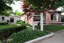 A photo of a historic brick house and attached museum. The middle of the photo displays the museum sign "Chapman Museum."