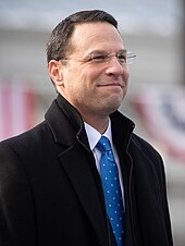 Shapiro pictured with glasses and suit, smiling