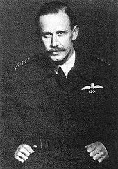 Half-length portrait of moustachioed man in military battle jacket, with aviator's wings on left breast pocket and four stripes on shoulders