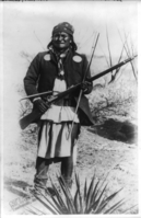 "Scene in Geronimo's camp...before surrender to General Crook, March 27, 1886: Geronimo, full-length portrait standing, facing left, rifle at port."