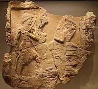 King Iddi(n)-Sin of the Kingdom of Simurrum, holding an axe and a bow, trampling a foe, facing Ishtar. Circa 2000 BCE. Israel Museum.[1]