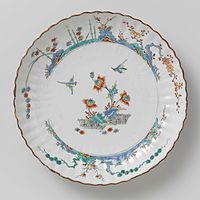 Chinese porcelain dish with ribbed edge, painted with bound hedges, bamboo blossoms and two flying birds on the mirror. 1700–c. 1750
