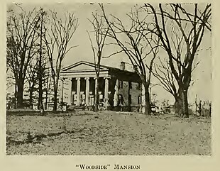 Historical photograph of Woodside Mansion with trees surrounding it. The front of the house has six columns in the Doric style, two stories tall. The ground slopes up gently from the photographer's location to the building.