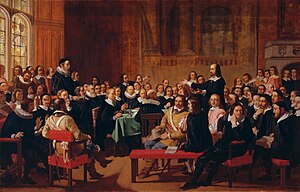 A painting of the Westminster Assembly in session. Philip Nye is standing and gesturing. Various figures are seated around a table. Prolocutor William Twisse is seated on a raised platform.