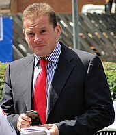 Waist-up shot of football manager Graham Westley holding some papers
