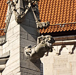 Gargoyle representing a comical demon at the base of a pinnacle with two smaller gargoyles, Visby, Sweden