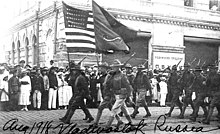 Soldiers parading with two flags, one American