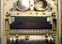 The processor chip (integrated circuit package) inside a 1980s Sharp pocket calculator, marked SC6762 1•H. An LCD is directly under the chip. This was a PCB-less design. No discrete components are used. The battery compartment at the top can hold two button cells.
