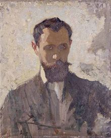 A head and shoulders portrait of a thirty something man, with a dark beard, facing towards the viewer