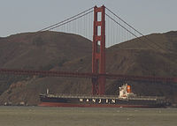 M/V Cosco Busan departing San Francisco under its new name, MSC Hanjin Venezia, approaching the Golden Gate Bridge. Repairs visible on her port side.