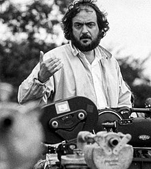 A black and white photograph of Kubrick above a camera while filming Barry Lyndon in 1975