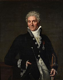 A white-haired man in a blue jacket, facing the viewer.