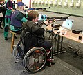 Para shooting with a rifle sitting in a wheelchair.