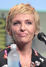 A photograph of Toni Collete. She has strawberry-blonde, over-shoulder length hair. She has a black jacket over a white dress, which has black polka dots.