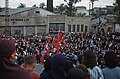 A crowd with some Turkish flags in front of a building