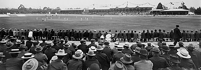 An early 20th-century cricket match, watched by a large crowd