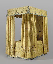 Golden yellow silk bed hangings on a canopied four-poster bed