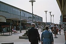 Pedestrians walking through a wide area between shop fronts