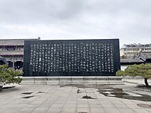 large stone monument with engraved Chinese characters, in an outdoor courtyard.