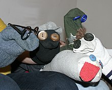 A number of literal sock puppets with buttons for eyes. One wears a pair of glasses. Another has yarn for hair.