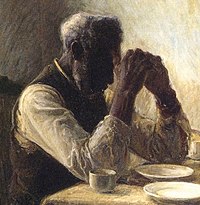 Elderly African-American man praying at a table
