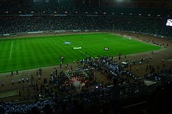 Flag bearers entering the pitch followed by both teams, Zamalek SC and Al-Zawra'a SC as well as a crowd of journalists and photographers, during the opening ceremony