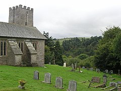 Stone building with square tower and gravestones in the foreground.