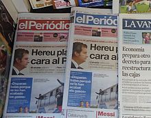 two stacks of El Periódico newspapers, one in Spanish, one in Catalan
