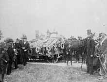 A group of people are gathered in front of a casket