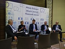 Five people sit in front of a banner at the "Minsk Dialogue" event