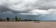 Pirogue on the Mekong under grey clouds before a storm