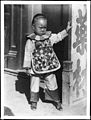 A small Chinese boy wearing a patchwork bib.