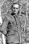 a man wearing a military uniform with various military decorations including an Iron Cross at his neck.