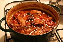a large casserole with pieces of chicken in a tomato and mushroom sauce