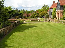 green lawn with trees to the left and a house on the right