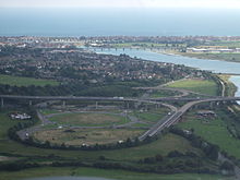 raised major road junction over fields and other roads with a wide estuary beyond