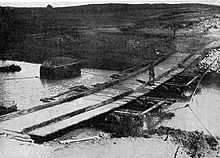 The bridge was constructed by the New Zealand Mounted Rifles Brigade. Long planks of wood were laid across the stream on empty wine casks; shorter planks were then laid on top crosswise to form a flat surface.