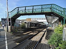 footbridge in the foreground and two-platform railway station beyond