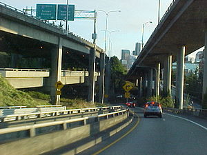 A freeway offramp in a city with a double-decker freeway to the left and an elevated freeway structure to the right