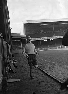 A footballer jogs around a pitch