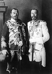 Two bearded men of identical height wear military dress uniforms emblazoned with medals and stand side-by-side