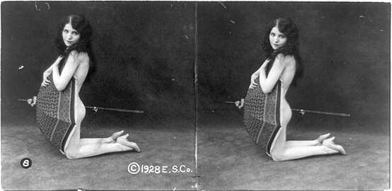 Unidentified nude model kneeling with an open umbrella obscuring her torso