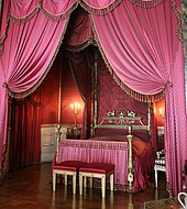Queen Charlotte's bed, scene from its right. It is clad in crimson silk, as is the alcove containing it.