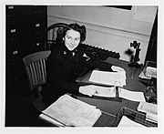 WAVE Y3c Ruth Beffre on duty at Navy Headquarters, New York City, 1943. Note candlestick phone, forms, and paper trays on desk.