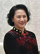 Nguyễn Thị Kim Ngân seen smiling while wearing a traditional Vietnamese dress in the colours red and burgundy.