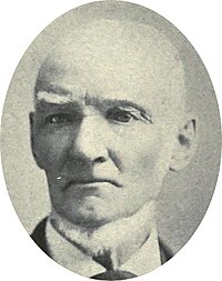 Portrait photograph of a bald man with bushy white eyebrows and a chinstrap beard