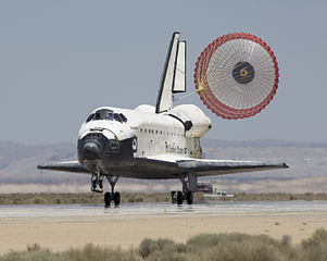 A parachute may be used to slow down craft, in this case the Space Shuttle Atlantis.
